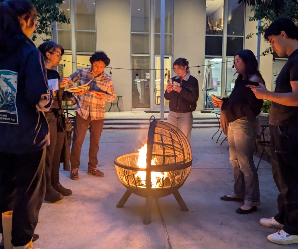 Students gather around a fire to read and burn prayers collected from the Little Chapel of Silence.